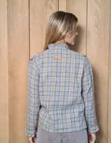 Camisa de manga larga con estampado de rayas verticales en tonos blanco y lila. Presenta cuello alto con volados, cierre frontal con doble botonadura y puños con volados.