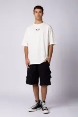 Remera de corte oversize color blanco hueso, con cuello redondo y estampa pequeña centrada en el pecho que presenta dos figuras de caballos alados.