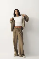 Pantalón cargo de tejido liviano color verde militar, con cintura elástica y cordón ajustable. Presenta diseño de piernas holgadas y bolsillos laterales con solapa.