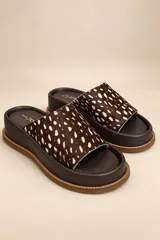 Sandalias de cuero vacuno con plataforma baja, capellada ancha de pelo con estampado animal print tipo dálmata en tonos marrón oscuro y blanco, y plantilla marrón.