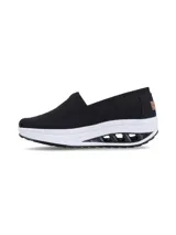 Zapatillas tipo slip-on Hush Puppies modelo Angelo, color negro, confeccionadas en tela canvas con elástico en el empeine para un calce sencillo. Poseen una suela de plataforma con tecnología de amortiguación y plantilla de memory foam de alta densidad.