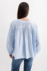 Camisa color crema de algodón con bordado calado, escote en V y mangas largas abullonadas.