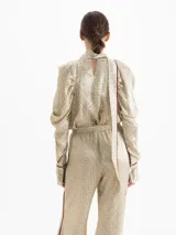 Top de seda con estampado floral pequeño, cuello alto con lazo integrado, mangas largas abullonadas con frunces en los hombros y puños camiseros con botones. Presenta detalles de ribete en color contrastante.