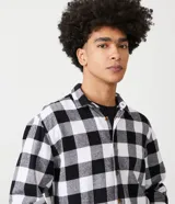 Camisa de manga larga confeccionada en franela de algodón, con estampado de cuadros en rojo y negro, cuello inglés y cierre frontal con botones.