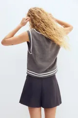 Short pollera de sarga gris oscuro con diseño tableado, rayas finas verticales y botones forrados decorativos en la parte delantera.