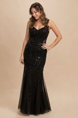 Vestido de gala largo color negro, con corte sirena y escote en V. Está confeccionado con una base de tela bordada con lentejuelas y presenta paneles laterales de tul transparente. La falda termina en un diseño acampanado con capas de tul.