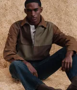 Chaqueta Marfinno de corte recto con diseño de bloques en tonos tierra, confeccionada en poliuretano con base de poliéster. Presenta cuello camisero estructurado, cierre frontal con zíper, mangas largas y forro interior con bolsillo funcional.