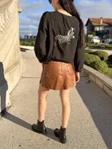 Blusa negra de corte holgado con mangas largas abullonadas y bordado de cebra en la espalda.