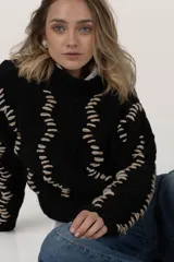 Sweater tejido a mano con lana merino color negro y bordado con lana color crudo. Es corto, a la cintura y de cuello alto.