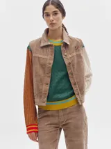 Chaleco de pana color beige con cierre frontal de botones metálicos, cuello camisero y detalle de bandera insignia en el pecho.