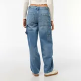 Jean baggy de tiro medio color azul claro con efecto desteñido y roturas en la rodilla izquierda. Presenta bolsillos laterales estilo carpintero y presillas para cinturón.
