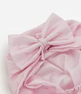 Gorro turbante de satén color rosa con diseño estampado sutil y detalle de moño grande al frente.