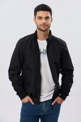 Campera liviana de nylon color azul marino, con cuello alto, cierre frontal y puños y dobladillo en elástico tejido.