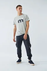 Pantalón cargo color beige, corte slim, con bolsillos laterales con botón, cierre con botón y puños en los tobillos.