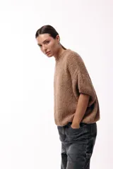 Sweater de tejido de punto grueso con silueta amplia y mangas 3/4. Presenta un cuello redondo y una textura rústica, ideal para un look invernal.