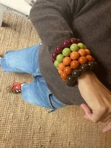Pulsera elástica compuesta por cuentas esféricas de resina en tonos verde lima, naranja y bordó.