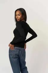 Remera de manga larga blanca, confeccionada en jersey liviano de tacto suave, con escote en V limpio y calce que acompaña el cuerpo.