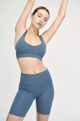 Top deportivo azul con escote redondeado y espalda cruzada.