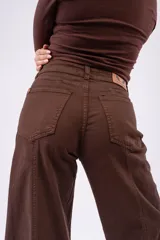Jean wide-leg color marrón chocolate, con tiro medio, bolsillos frontales y traseros, y costuras decorativas verticales a lo largo de las piernas.