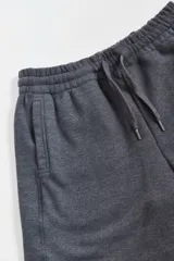 Bermuda de algodón y poliéster en color gris melange, con cintura elástica y bolsillos laterales. Presenta una etiqueta pequeña con el logo de la marca en el bolsillo trasero.