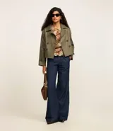 Trench coat de poliuretano color verde militar, con cuello de solapa, diseño cruzado y cierre frontal de doble botonadura.