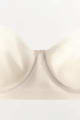 Sujetador de color blanco hueso o crema, con aros y copas moldeadas, corte recto en el bajo y tirantes finos ajustables y extraíbles.