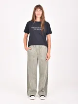 Remera gris oscuro de manga corta con cuello redondo. Presenta un estampado frontal con dos figuras femeninas estilizadas, una vestida de rosa con una estrella blanca y la otra con un look negro y rojo.