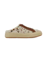 Zueco destalonado de estilo deportivo, confeccionado en cuero con pelo con estampado animal print tipo vaca en tonos blancos y marrones. Posee cordones marrones, detalles en cuero marrón y suela de plataforma de goma en tono tostado.