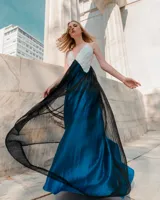 Vestido largo de fiesta con escote en V, parte superior blanca bordada con pétalos y falda plisada azul.