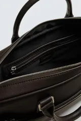 Maletín negro con textura grabada, diseño estructurado y asas de mano. Cuenta con cierre principal de cremallera, bolsillo frontal plano y bolsillo interior para dispositivos electrónicos de hasta 13 pulgadas. Incluye asa de hombro ajustable y extraíble.