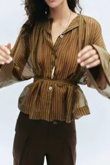 Camisa marrón a rayas con cuello redondo, mangas largas anchas y puños rectos. Cuenta con cierre frontal de botones y un lazo cinturón ajustable del mismo tejido en la cintura.