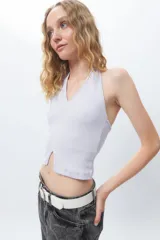 Crop top blanco de algodón, sin mangas, con cuello halter y abertura en el frente.