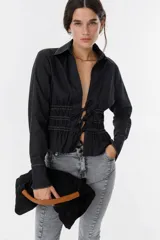 Bolso de mano tipo clutch, color negro, con asa rígida color marrón.