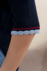 Buzo de tejido de punto en color gris claro, con diseño holgado, mangas tres cuartos con puños acanalados y detalle de línea en color contrastante en el ruedo.