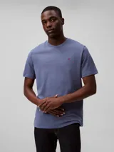 Remera de manga corta color azul, hecha de algodón liso, con cuello redondo y el monograma de Calvin Klein bordado en rojo en el pecho.