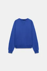 Sudadera azul con efecto lavado, cuello redondo y manga larga, con detalle de costura en V en el escote y ribetes elásticos en puños y cintura.