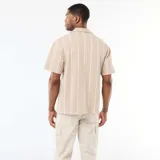 Camisa de manga corta color beige con diseño de rayas verticales blancas, cuello tipo cubano y cierre frontal con botones.