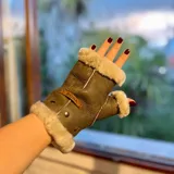 Mitones de cuero napa y lana color marrón, sin dedos, con detalles de corderito sintético blanco en los bordes y el pulgar. Incluye una etiqueta de cuero con la marca grabada.