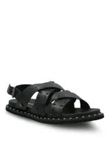 Sandalias negras de cuero con tiras cruzadas, tachas metálicas aplicadas y suela de EVA. Cuentan con tira ajustable en el talón con hebilla y ribete con tachas en la plataforma.