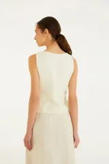 Chaleco color crema con escote en V y cierre frontal con botones. Confeccionado en viscosa, lino y algodón.