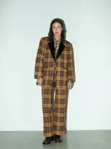 Blazer oversize con estampado cuadrillé en tonos marrones y amarillos, con cuello de terciopelo negro, dos bolsillos delanteros y forro de satén.