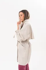 Trench de gabardina Tencel color beige, de silueta relajada, con cierre frontal de botones, lazo desmontable y regulable en la cintura, bolsillos amplios y lazos en los puños.