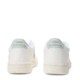 Championes urbanos New Balance, modelo Pop N Pack Leather, de color blanco con detalles en verde pastel en el logo lateral y la suela. Presentan una silueta clásica de corte bajo con perforaciones en la puntera y cierre de cordones.
