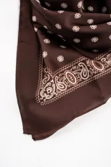 Pañuelo tipo bandana de color marrón con estampado paisley en los bordes y lunares blancos en el centro.