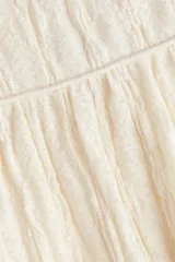 Pollera evasé midi de punto texturizado en color blanco, con elástico revestido en la cintura y costura fruncida con ribete bajo la cadera.