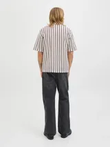 Camisa resort de manga corta color beige, con patrón geométrico de rayas verticales en tonos bordó, cuello camisero, cierre frontal de botones y calce relajado.