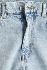 Jean de cinco bolsillos en denim de algodón rígido, corte holgado con cierre y botón. Cuenta con piernas amplias de diseño curvado, raya marcada y bajo deshilachado.
