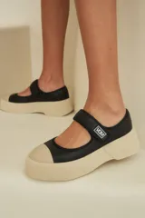 Guillerminas negras de cuero con puntera y suela color crema de goma.