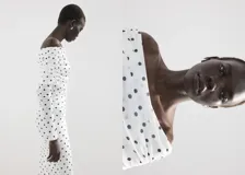 Vestido midi entallado de color blanco con estampado de lunares negros, escote palabra de honor con solapa drapeada y manga larga.