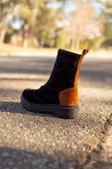 Bota de caña media de cuero color negro con detalles en marrón y suela track.